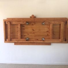 a wooden shelf mounted to the side of a wall with two hooks on each end