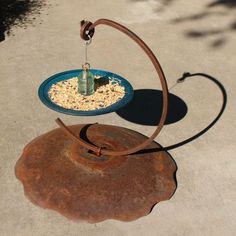 a bird feeder on top of an old rusted metal bowl with water in it