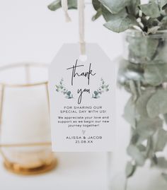 a thank you tag hanging from a vase filled with greenery