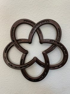 four horseshoes are arranged in the shape of a flower on a white wall background