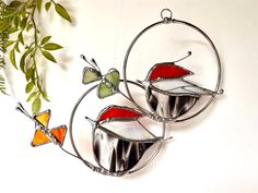 three colorful stained glass ornaments hanging on a wall next to a potted green plant