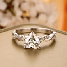 a diamond ring on top of a table with white flowers in the backgroud