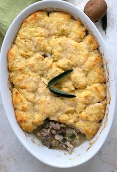 a casserole dish with meat and vegetables in it on a white tablecloth