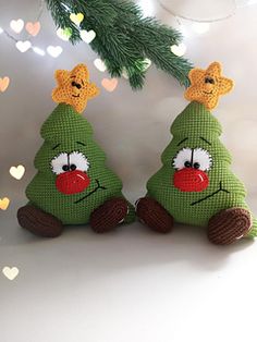 two green christmas trees sitting next to each other on top of a white table with hearts