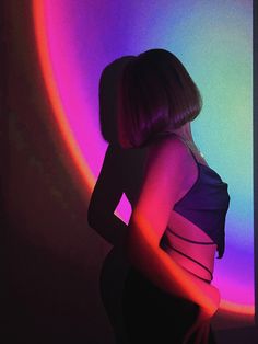 a woman standing in front of a rainbow colored wall with her back to the camera