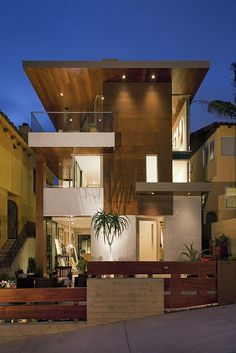 a modern house is lit up at night with lights on the windows and balconies