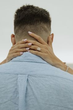 a woman covering her face behind a man's back with his hands on his neck