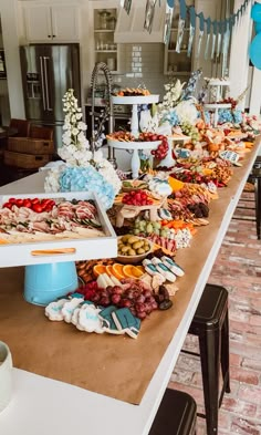 a long table filled with lots of food on top of a white counter next to a brick floor