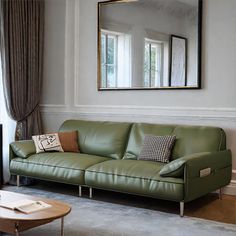 a green leather couch sitting in front of a mirror