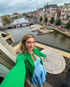 a woman standing on top of a balcony next to a river