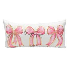 three pink bows on a white pillow with gold trimmings, one in the shape of a bow