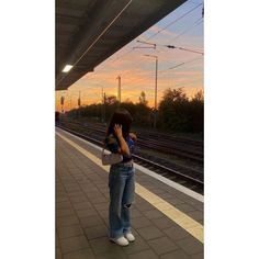 a woman standing on the side of a train station holding her head in her hands