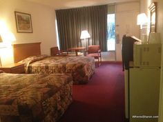 two beds in a hotel room with red carpet and lamps on either side of them