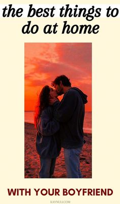 a man and woman standing next to each other on a beach with the sun setting behind them