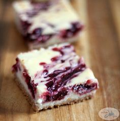 two pieces of cheesecake with blueberry topping sitting on a wooden table next to each other