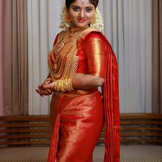 a woman in a red and gold sari is standing with her hands on her hips