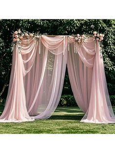 an outdoor wedding ceremony with pink drapes and flowers on the top, along with greenery