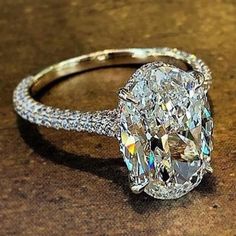 an oval cut diamond ring on a wooden surface