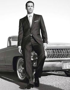 a man in a suit standing next to a car