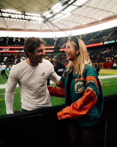 a man and woman standing next to each other at a football game