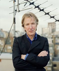 a man with his arms crossed standing in front of an array of wires and telephone poles