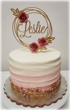 a white cake with pink frosting and gold decorations on top that says jeslie