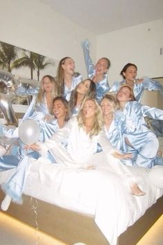 a group of women dressed in blue and white posing for a photo on a bed