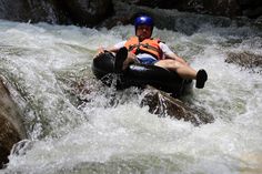 a man riding on the back of a raft down a river