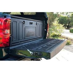 the back end of a pickup truck with its cargo compartment open and it's tail light on