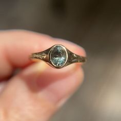 a person holding a ring with a blue topazte stone in it's hand