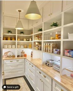 a kitchen filled with lots of white cupboards and counter top space next to a light fixture