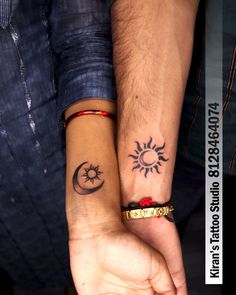 two people are holding hands with tattoos on their wrists and the other hand has a sun and moon tattoo on it