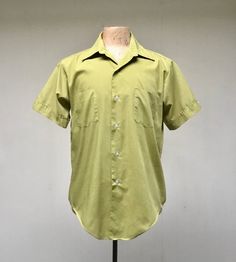 * Men's casual shirt c 1970s* Green polyester-cotton blend fabric * Medium pointed collar* Double chest patch pockets * Short, set-in sleeves with sewn down notched cuff with button detail* Action pleats below back yoke* 6 button front closure* Long tailsLabel: Master Built - Permanent Press - 15 1/2Excellent conditionChest: 44Shoulder: 18Sleeve: 9Length: 31 (center back)Garments are flat-measured. Please compare these measurements to another flat-measured garment that fits you correctly for siz Fitted Cotton Camp Shirt With Spread Collar, Retro Cotton Collared Camp Shirt, Retro Shirt With Johnny Collar And Relaxed Fit, Vintage Cotton Shirt With Johnny Collar, Vintage Cotton Short Sleeve Shirt With Camp Collar, Retro Cotton Camp Shirt With Pockets, Classic Green Cotton Camp Shirt, Retro Cotton Camp Shirt For Spring, Retro Collared Short Sleeve Shirt Relaxed Fit