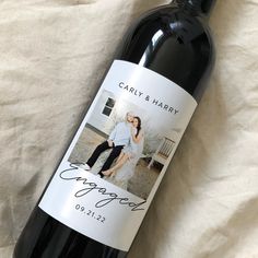 a bottle of wine sitting on top of a bed next to a white sheet covered floor