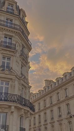 an ornate building with balconies and balconyes against a cloudy sky at sunset