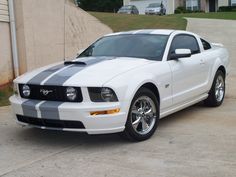 a white and black mustang parked in front of a house