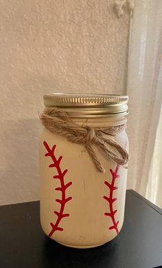 a mason jar with baseballs painted on the inside and string tied around the lid