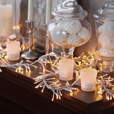 candles are lit in front of glass jars with snowflakes on them and lights