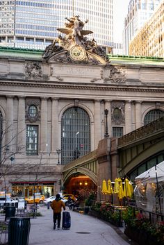 people are walking in front of an old building with many windows and yellow umbrellas