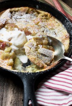 a cast iron skillet filled with fruit cobbler and ice cream on top of a striped towel