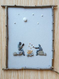 two small figurines sitting on top of a wooden frame