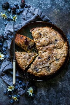 a blueberry coffee cake on a plate with a knife and some berries around it