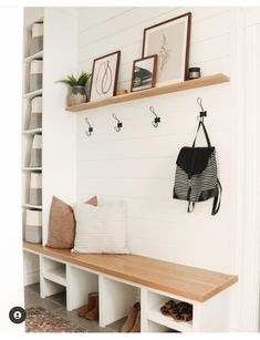 a wooden bench sitting in front of a white wall with hooks on it's sides