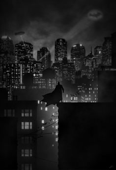 a black and white photo of a batman standing on top of a building at night