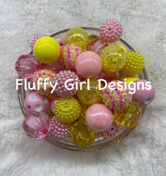 a glass bowl filled with lots of different colored plastic beads on top of a white blanket