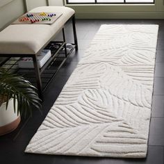 a large white rug on the floor in front of a window with a plant next to it