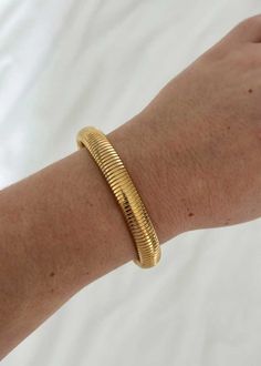 A stretchy gold plate bracelet. Gold Stackable Stretch Bangle Bracelet, Flexible Gold Bracelet For Everyday Wear, Gold Everyday Bracelets, Gold Stretch Bracelet For Everyday Wear, Adjustable Gold Stretch Bracelet For Everyday, Everyday Gold Stretch Bangle Bracelet, Everyday Gold Stretch Bracelet, Everyday Flexible Gold Bracelet, Trendy Gold Stackable Stretch Bracelet