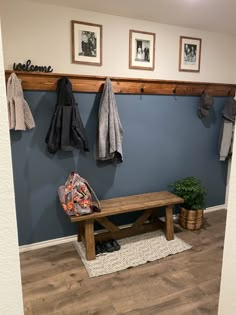 a bench and coat rack in a room with blue walls, wood flooring and pictures on the wall