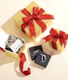 three gift boxes with red ribbon on top of each box and one has a ring in it