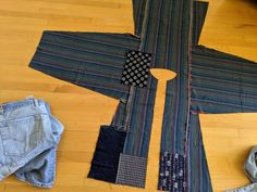 a pair of jeans laying on top of a wooden floor next to a piece of cloth